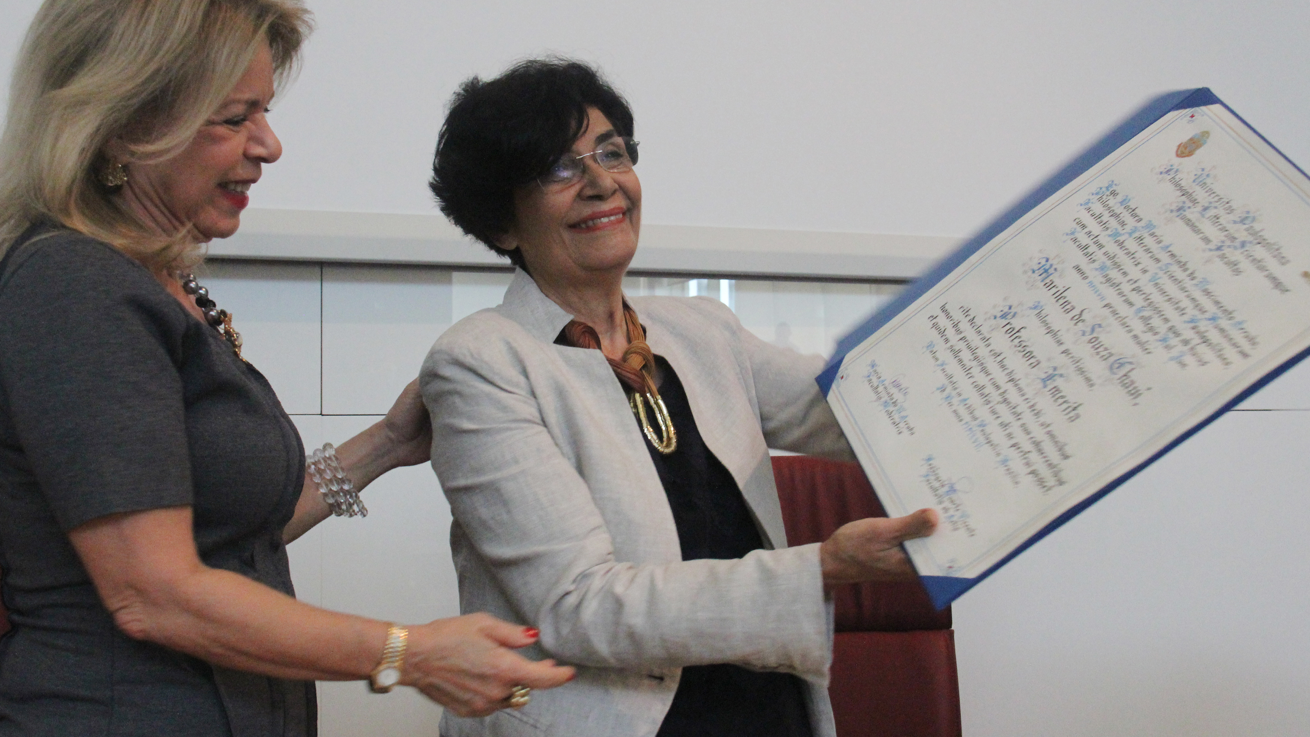 À direita, a diretora da FFLCH, Maria Arminda, e, à esquerda, Marilena Chaui mostrando o diploma de professora emérita 