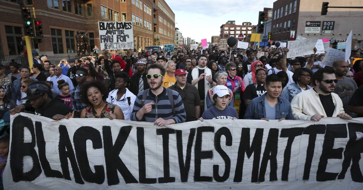 Imagem contento manifestantes protestando contra o racismo e um cartaz dizendo "Black Lives Matter"