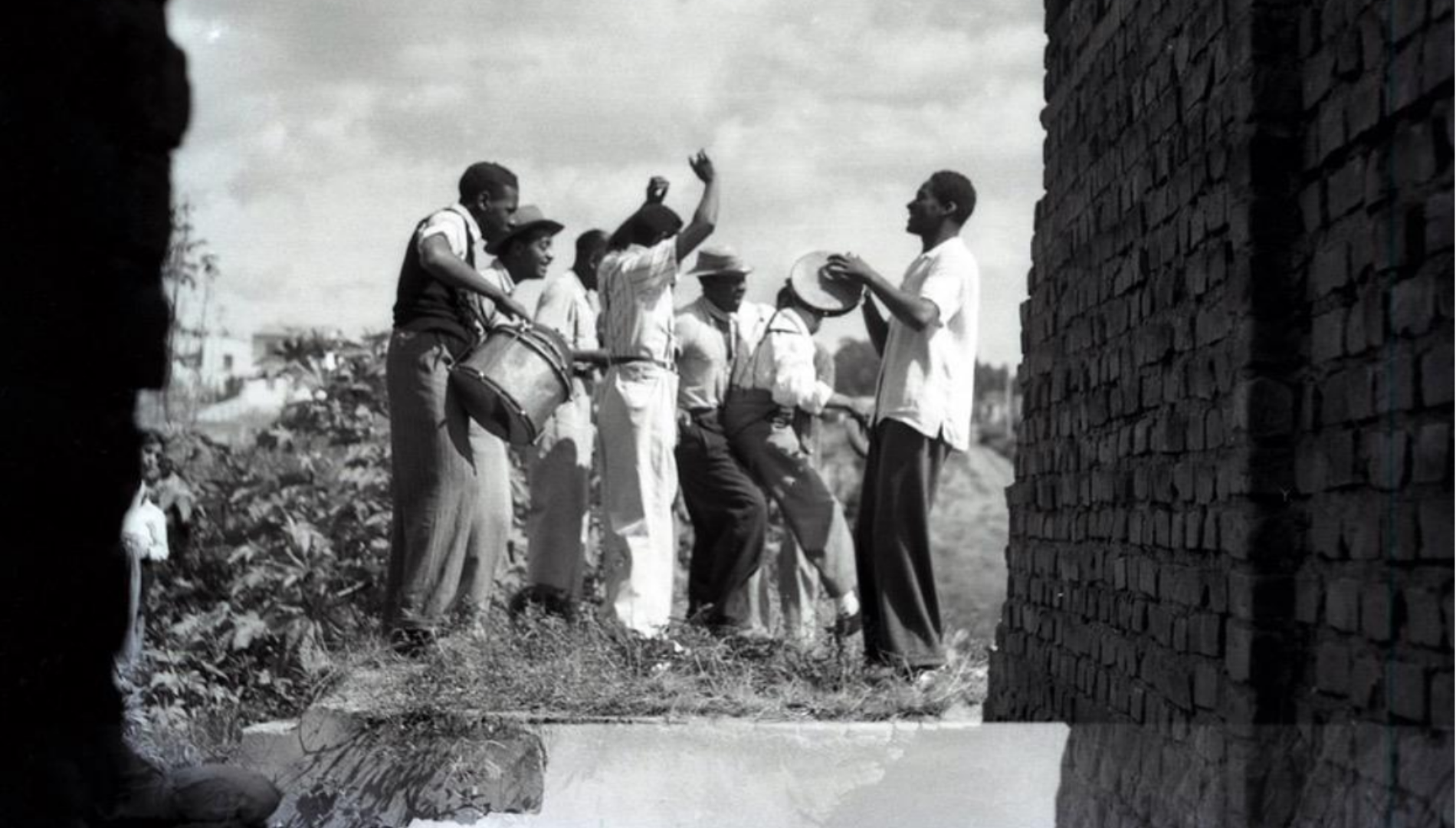 Foto em preto e branco de pessoas dançando em uma roda de samba