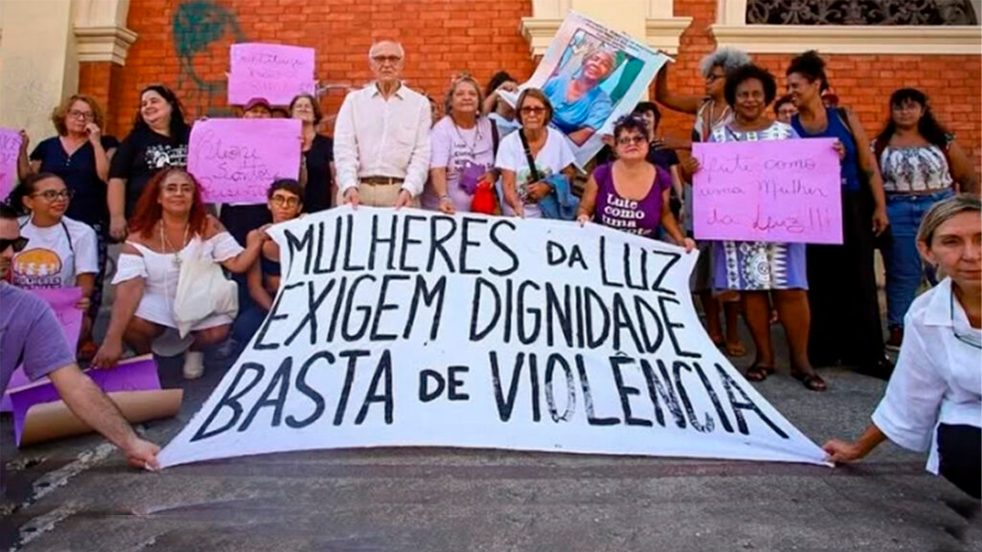Mulheres segurando cartaz: Mulheres da Luz exigem dignididade basta de violência